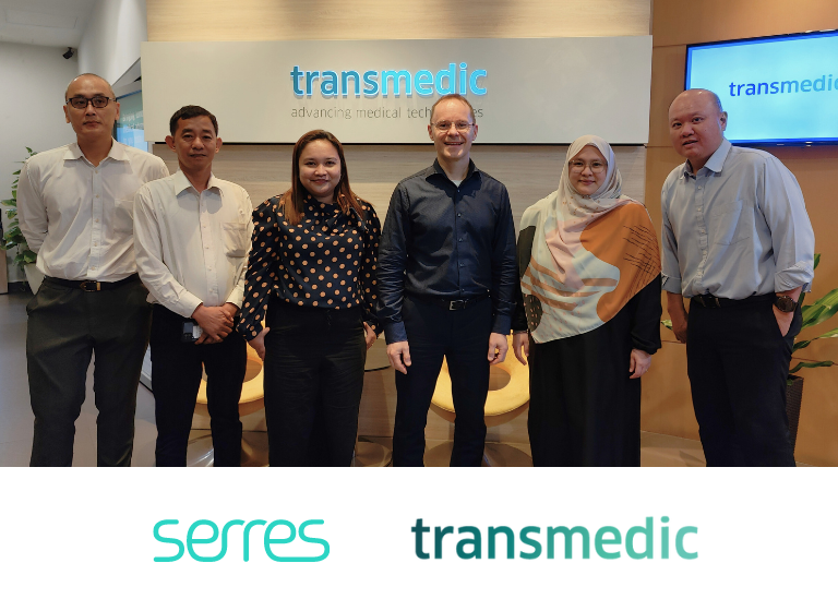 People standing in front of the Transmedic logo smiling.